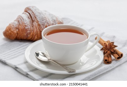Tea, fresh French croissant, star anise and cinnamon sticks. Cafe breakfast concept.