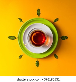 Tea in glass cup with green leaves  on orange background. Time concept. - Shutterstock ID 396190531