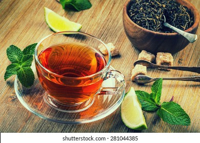 Tea in a glass cup, mint leaves, dried tea, sliced lime, cane brown sugar 