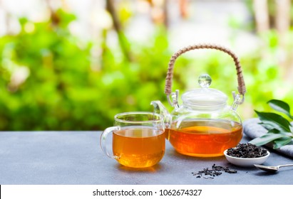 Tea in glass cup and teapot on summer outdoor background. Copy space.