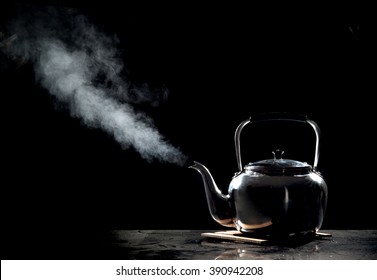 Tea Kettle With Boiling Water On A Black Background