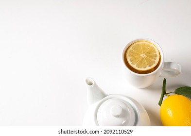 Tea With Lemon, Fresh Healthy Tea, Antioxidant Detox Lemonade, Green Leafy Lemon Next To White Porcelain Teapot On White Isolate Background, A Cup Full Of Tea With Sliced Lemon