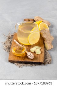 Tea lemon ginger with honey in a glass cup on a wooden board on a light background - Shutterstock ID 1877188963