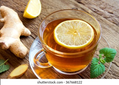 Tea with lemon, ginger, honey and mint leaves in cup over rustic wooden background