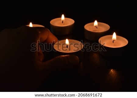 Tea light candles in the dark background.  Hand putting a candle on the table.