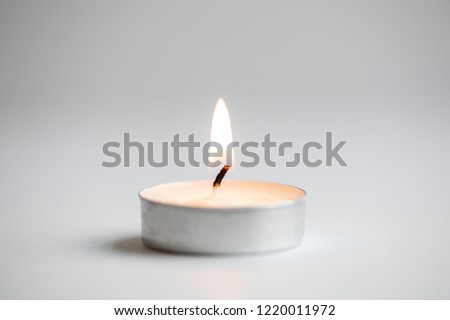 Tea light candles lit with flame on a white background