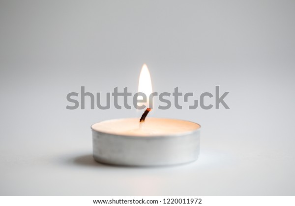Tea\
light candles lit with flame on a white\
background