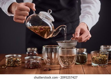 Tea master pouring green tea with rose buds into glass cups through a sifter. Brewing and serving perfect hot drink at a restaurant.
