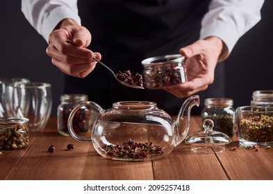 Tea master putting rose buds into a glass teapot. Preparation of hot drink with rich flower flavour. Tea party at a restaurant. - Shutterstock ID 2095257418