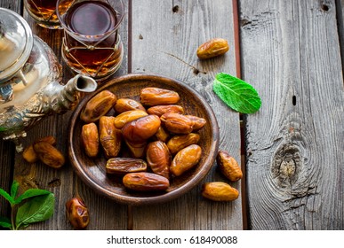 Tea with mint in arab style and dates on wooden table. Selective focus.