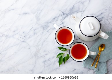 Tea in mugs with teapot on marble background. Copy space. Top view.