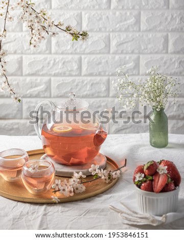 Tea pot on white background, strawberries and white flowers