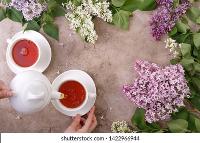 Tea Set And Flower Decor On A Textural Background. Pouring Tea Into A Mug And Place Under The Text. View From Above. Flat Lay. The Concept Of Tea Drinking. Vintage.