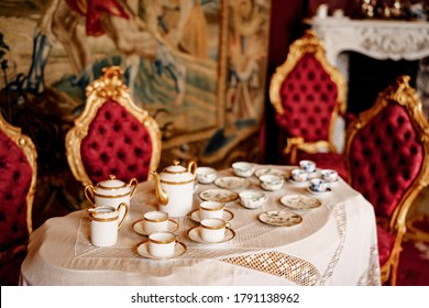 A tea set for four on a table with lace tablecloth and chairs with gold rim and red trim. - Powered by Shutterstock - Get 15% off with code: PIKWIZARD15