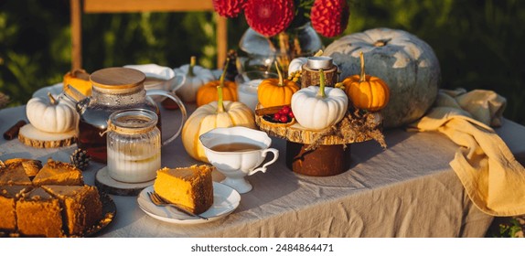 Tea setting with handmade pie. Beautiful view of garden wooden furniture with basket, soft blanket and burning candles. Outdoors fall family party, cozy autumn interior. Pumpkins, red dahlia banner - Powered by Shutterstock