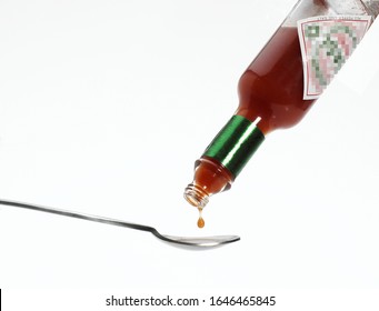 Tea Spoon with Tabasco, Hot Pepper Sauce, Bottle against White Background  