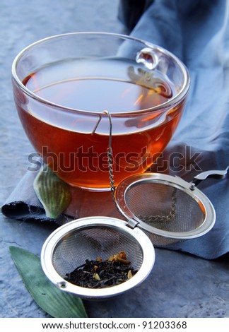 tea strainer with a fragrant black tea and cups in the background