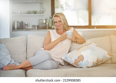 Tea Time Is Me Time. Portrait Of A Mature Woman Enjoying A Warm Beverage While Relaxing On The Sofa At Home.