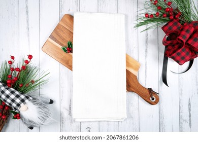 Tea Towel Kitchen Product Mockup. Christmas Farmhouse Theme SVG Craft Product Mockup Styled With Gift With Buffalo Plaid Bow And Farmhouse Style Gnomes Against A White Wood Background.