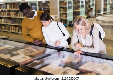 Teacher And Adult Students View Rare Books In A Library Showcase. High Quality Photo