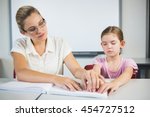 Teacher assisting blind student in library at school