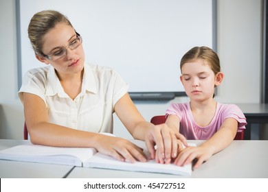 Teacher assisting blind student in library at school - Powered by Shutterstock