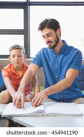 Teacher Assisting Blind Student In Library At School