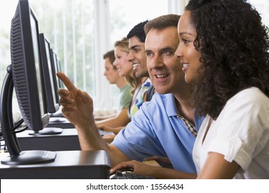 Teacher Assisting College Student In A Computer Lab