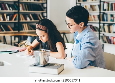 Teacher Assisting Girl With Homework In Library. Tutor Working With Middle School Student. 