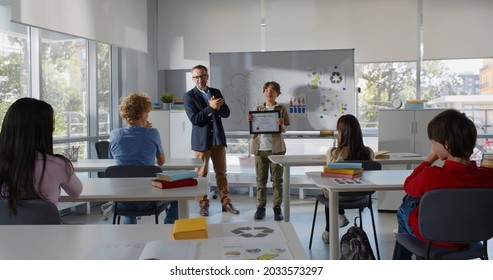 Teacher Award Teen Student For Best Presentation And Classmates Congratulate. Teenage Student Win Prize And Friends Applaud Celebrating Together In Classroom