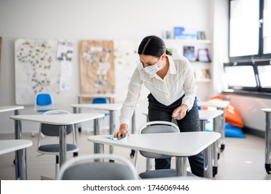 Teacher back at school after covid-19 quarantine and lockdown, disinfecting desks. - Shutterstock ID 1746069446