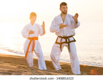 Teacher And Boy Doing Karate Poses At Sunset Sea Shore