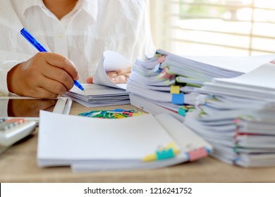 Teacher Is Checking Student Homework Assignment And Report On Desk In School For Score. Unfinished Paperwork Stacked In Archive With Color Papers And Paper Clips. Education And Business Concept.