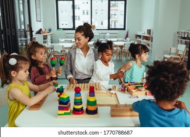Teacher and cheerful children are playing with toys at the kindergarten