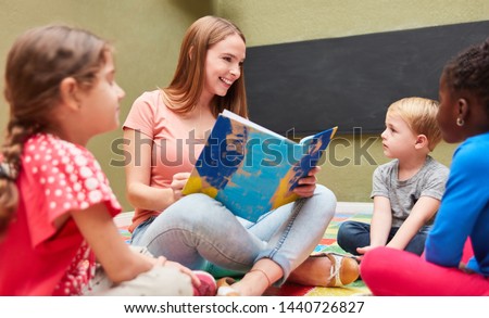 Teacher or childminder reading from a children's book in kindergarten