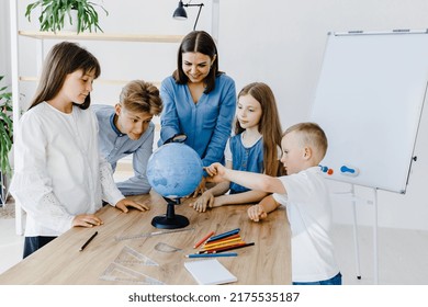 Teacher and children in class are looking at globe, teacher helps explain the lesson to the children in the class at a desk. Educational school process, bright room and interesting learning - Powered by Shutterstock