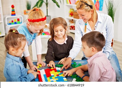 Teacher and children are playing a board game in the classroom.