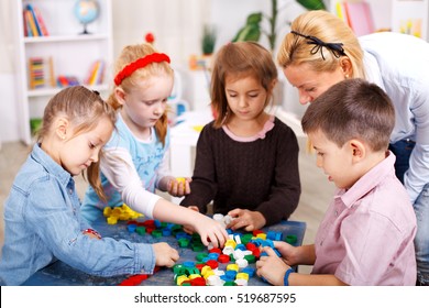 Teacher and children are playing with puzzle in the classroom