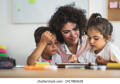 Teacher with children using digital tablet in preschool classroom - Education and technology concept