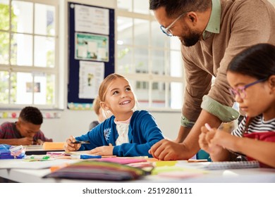 Teacher in classroom giving feedback to smiling schoolgirl while studying at desk. Cute little girl in classroom listening to teacher while writing notes in notebook. Teacher helping primary student. - Powered by Shutterstock