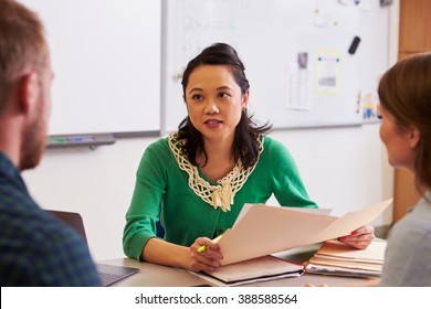 Teacher At Desk Talking To Adult Education Students