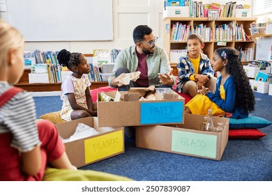 Teacher educates the elementary class in separating waste: paper, plastic and glass for recycling. Group of children participate in the separation of plastic, paper and glass waste to save the palnet. - Powered by Shutterstock