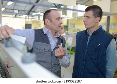 Teacher Encouraging Apprentice Using Machinery