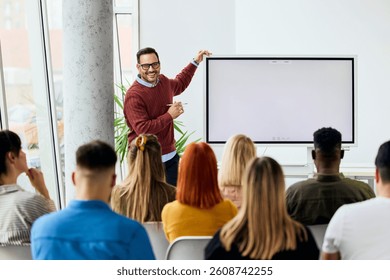 Teacher explaining concepts to students using whiteboard in modern classroom setting.