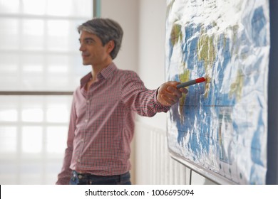 Teacher Explaining Geographic Map In A Classroom.