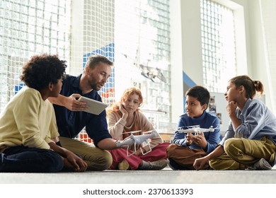 Teacher explaining group of children safety precautions before launching flying drones