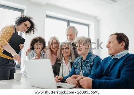 Teacher explaining senior students how to work with laptop, internetbanking. Elderly people attending computer and technology education class. Digital literacy.