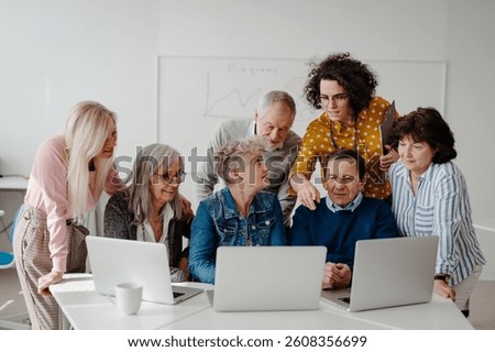 Teacher explaining senior students how to work with laptop, internetbanking. Elderly people attending computer and technology education class. Digital literacy.