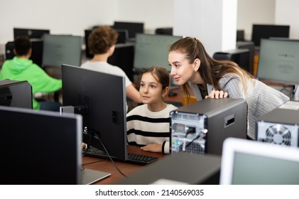 Teacher Explaining Task Solution To Young Girl During Computer Science Lesson In School.