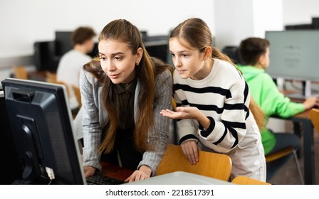 Teacher Explaining Task Solution To Young Girl During Computer Science Lesson In School.